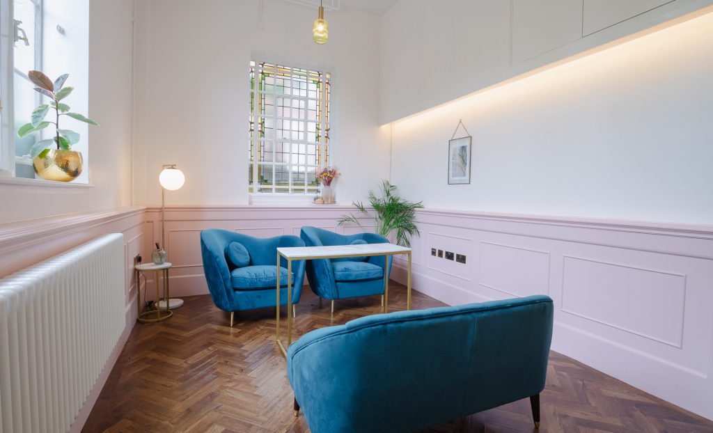The Canonbury Suite at Islington Town Hall set up for ceremonies, viewed from the witnesses' perspective, with pink walls, peacock blue velvet chairs, wooden floor and large windows