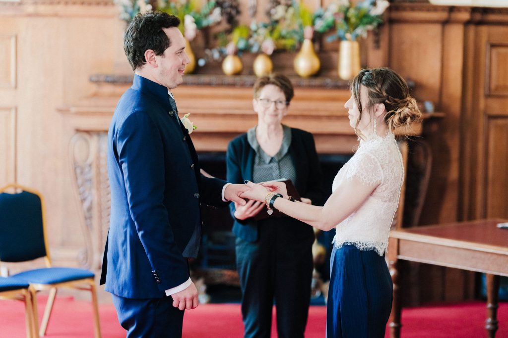 A couple exchange rings at their wedding in the traditional Richmond Suite at London's Islington Town Hall